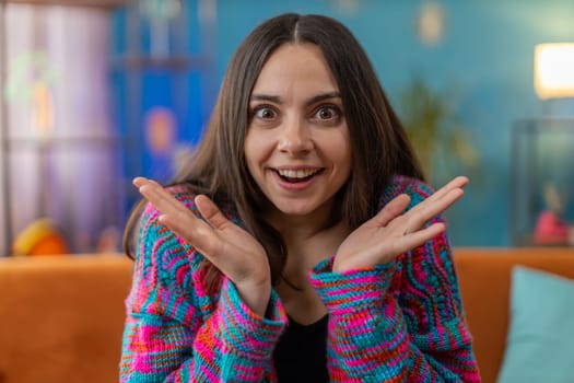 Oh my God, Wow. Excited amazed young woman surprised looking at camera with big eyes, shocked by sudden victory, good win news, celebrating. Portrait of Caucasian girl at home apartment room on sofa