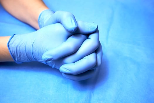 The hands of a medic in blue protective gloves