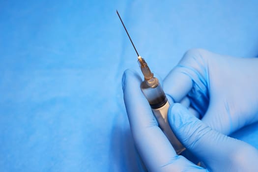 Hands of a medic in gloves hold a syringe