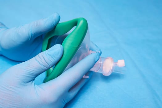 Hands of a medic in gloves and an anesthesia mask close up