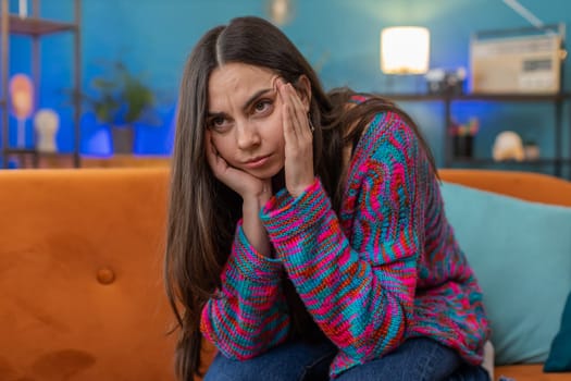 Displeased woman rubbing temples to cure headache problem, suffering from tension and migraine, stress grimacing in pain high blood pressure at home room apartment. Caucasian girl on couch. Lifestyles