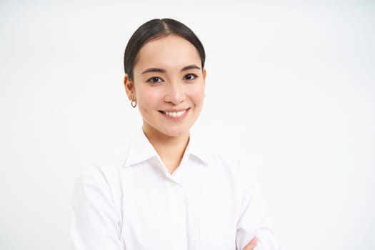 Portrait of korean businesswoman in shirt, smiles at camera, concept of corporate people and business, stands over white background.