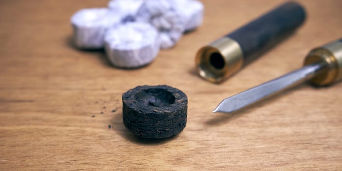 Pu-erh tea in the form of a round pressed briquette and a knife for grinding it on a wooden table