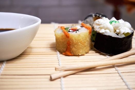 Sushi, chopsticks and a bowl of soy sauce on a bamboo mat. Selective Focus