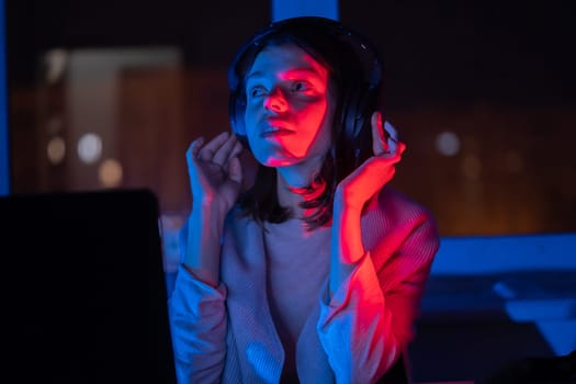 A young girl holds headphones and is listening and composing music, a woman sits with a laptop by the window in her room, works and enjoys the sound.