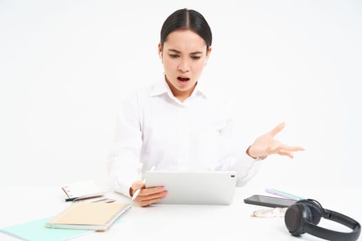 Angry korean woman shouting at employee on video chat, has intense conversation online, looks frustrated at digital tablet, white background.