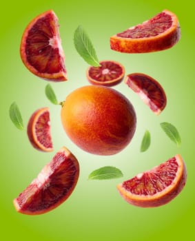Whole and pieces of ripe red orange, green mint leaves on a green background