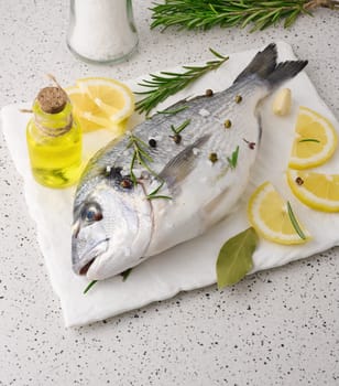 Raw whole dorado fish on white board and spices for cooking, top view on white table