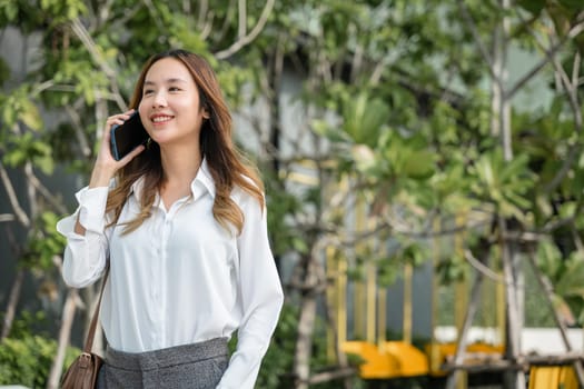 Beautiful young Asian woman calling and talks on telephone or mobile phone in city, Portrait of businesswoman smiling talking on mobile phone, people and technology communication concept