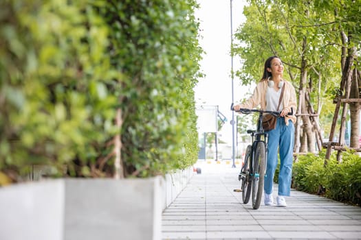 Happy female smiling walk down the street with her bike on city road, ECO environment, Lifestyle Asian young woman walking alongside with bicycle on summer in countryside outdoor, healthy travel