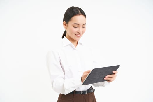 Corporate and young entrepreneurs concept. Successful businesswoman using digital tablet, prepares for meeting, looks at business concept on her gadget.