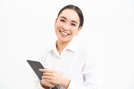 Corporate asian woman, manager using digital tablet, working on gadget, checking charts, company statistics, standing over white background.