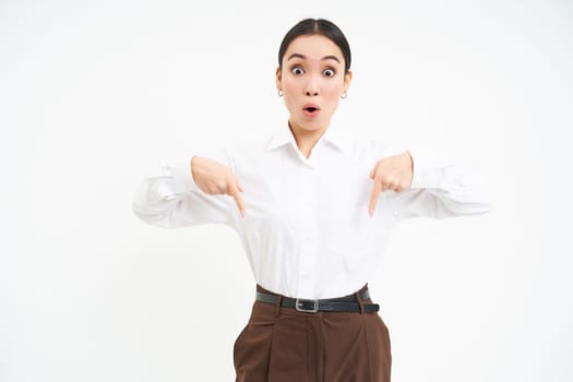 Image of korean businesswoman points finger at banner, shows advertisement, white studio background.