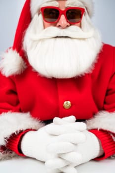 Portrait of santa claus sitting with his arms folded at a white table