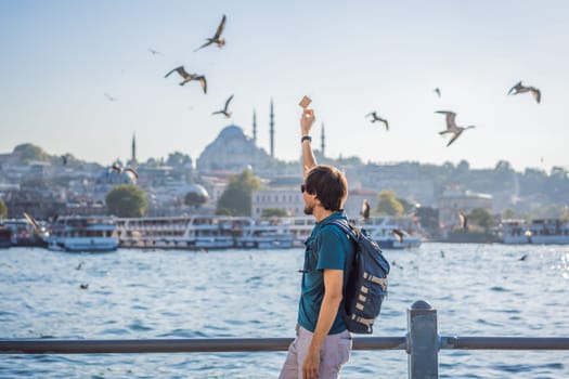 Young man traveler in pinc dress enjoying great view of the Bosphorus and lots of seagulls in Istanbul.
