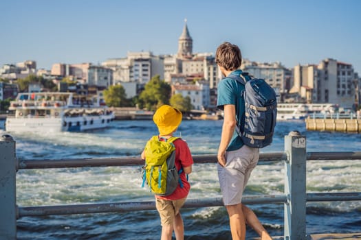 Father and son tourists enjoy Istanbul city skyline in Turkey, Beyoglu district old houses with Galata tower on top, view from the Golden Horn.