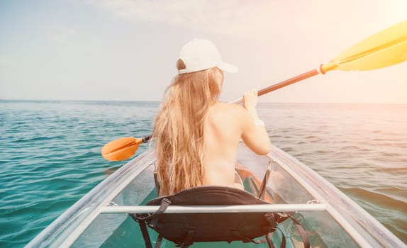 Woman in kayak back view. Happy young woman with long hair floating in transparent kayak on the crystal clear sea. Summer holiday vacation and cheerful female people having fun on the boat.