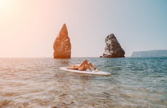 Close up shot of beautiful young caucasian woman with black hair and freckles looking at camera and smiling. Cute woman portrait in a pink bikini posing on a volcanic rock high above the sea