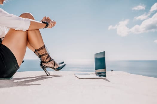 Happy girl doing yoga with laptop working at the beach. beautiful and calm business woman sitting with a laptop in a summer cafe in the lotus position meditating and relaxing. freelance girl remote work beach paradise