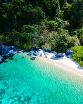 couple on beach in swimwear at Koh Adang Island near Koh Lipe Island Southern Thailand with turqouse colored ocean and white sandy beach Tarutao National Park