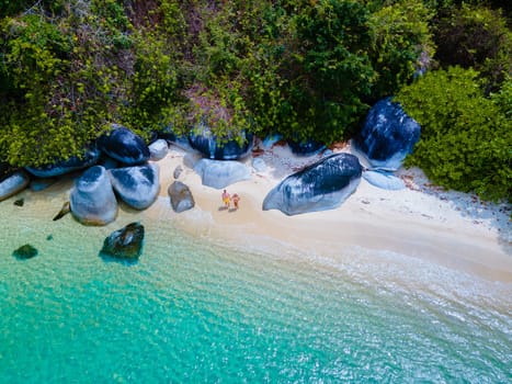 couple on beach in swimwear at Koh Adang Island near Koh Lipe Island Southern Thailand with turqouse colored ocean and white sandy beach Tarutao National Park