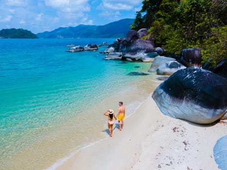 couple of men and women on the beach in swimwear at Koh Adang Island near Koh Lipe Island Southern Thailand with turqouse colored ocean and white sandy beach Tarutao National Park