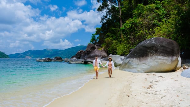 couple of men and women on the beach in swimwear at Koh Adang Island near Koh Lipe Island Southern Thailand with turqouse colored ocean and white sandy beach Tarutao National Park