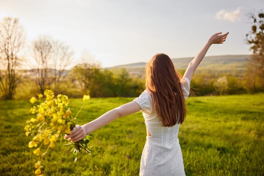 a girl in a light summer dress stands in a field with a bouquet of flowers raising her hands up. High quality photo
