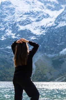 Young woman enjoying nature in Morskie Oko Snowy Mountain Hut in Polish Tatry mountains Zakopane Poland. Naturecore aesthetic beautiful green hills. Mental and physical wellbeing Travel outdoors tourist destination