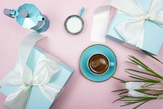 A cup of coffee and a gift box with a white bow on a pink background.