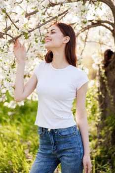 portrait of a happy woman with red hair in casual clothes enjoying the flowering of a fruit tree. High quality photo