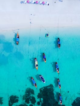 Longtail boats in the blue ocean of Koh Lipe Island Southern Thailand with turqouse colored ocean and white sandy beach