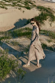 a slender woman in a long dress walks along a wild beach alone. High quality photo