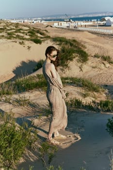 a slender woman in a long dress walks along a wild beach alone. High quality photo