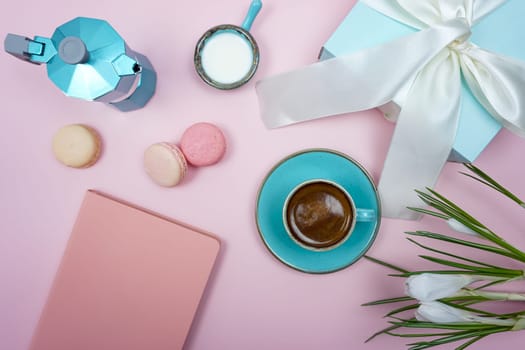 Good romantic morning. On the pink table there is a notebook, cookies, a cup of hot coffee and gifts in blue boxes with white bows.