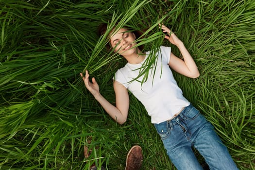 happy woman lying in tall grass biting leaves. High quality photo