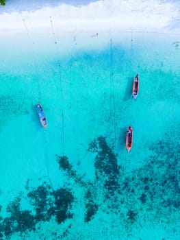 Longtail boats in the blue ocean of Koh Lipe Island Southern Thailand with turqouse colored ocean and white sandy beach at Ko Lipe.