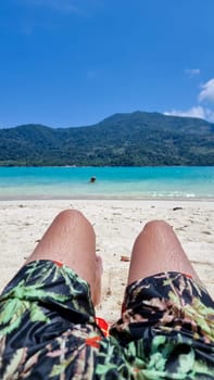 Young men in swim short at the beach of Koh Lipe Island Southern Thailand with turqouse colored ocean and white sandy beach at Ko Lipe.