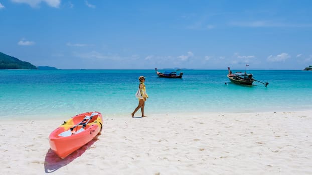 Koh Lipe Island Southern Thailand with turqouse colored ocean and white sandy beach at Ko Lipe. a Asian Thai woman on vacation in Thailand relaxing at the beach looking at the ocean