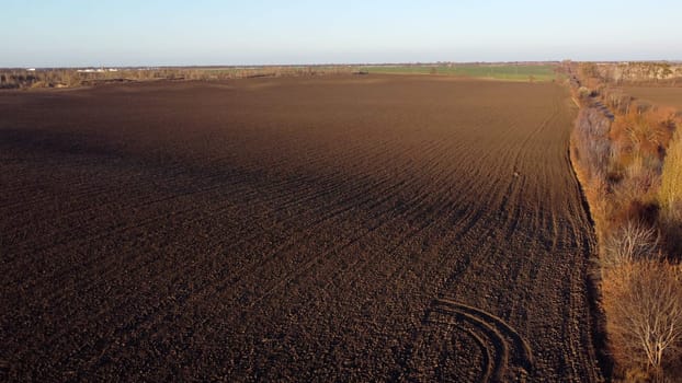 Landscape of plowed up land on an agricultural field on a sunny autumn day. Flying over the plowed earth with black soil. Agrarian background. Black soil. Ground earth dirt priming aerial drone view.
