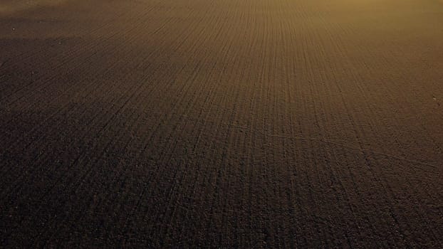 Landscape of plowed up land on an agricultural field on a sunny autumn day. Flying over the plowed earth with black soil. Agrarian background. Black soil. Ground earth dirt priming aerial drone view.