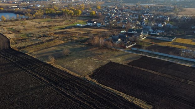 Houses, agricultural plowed fields, lakes ponds for growing fish, gardens, horticulture, home, village, city on sunny autumn day. Agrarian scenery. Beautiful rural country landscape. Aerial drone view