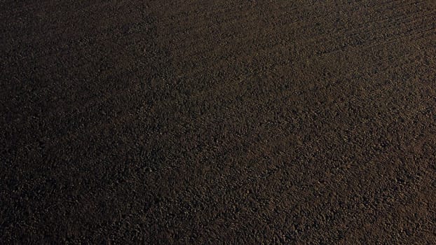 Landscape of plowed up land on an agricultural field on a sunny autumn day. Flying over the plowed earth with black soil. Black soil. Ground earth dirt priming aerial drone view. Agrarian background