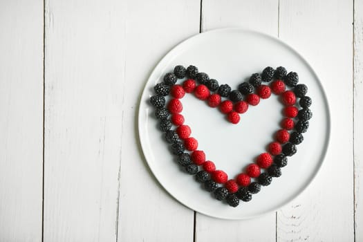 Nothing says romance like juicy ripe raspberries. High angle shot of berries in the shape of a heart on a plate