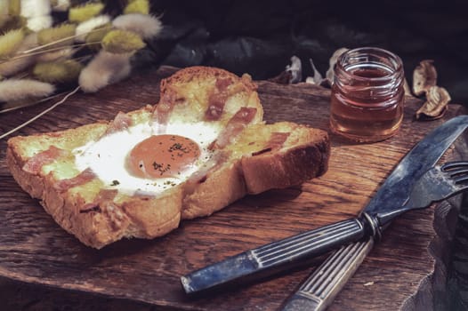 Homemade fried egg in a hole Bacon and Cheese toast serve with Honey on wooden cutting board. Sandwiches for breakfast, The concept of delicious food, Selective Focus.