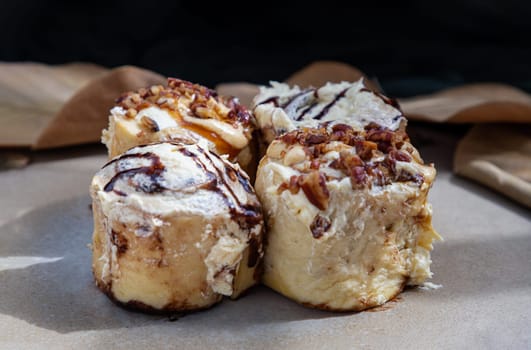 Close up of Two Soft Chocolate Buns topped with rich cream cheese frosting and Two Caramel Pecanbon topped with decadent caramel frosting and pecans on ceramic tray. The concept of delicious food, Selective Focus.