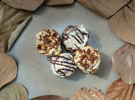 Two Soft Chocolate Buns topped with rich cream cheese frosting and Two Caramel Pecanbon topped with decadent caramel frosting and pecans on ceramic tray. The concept of delicious food, Top view, Selective Focus.