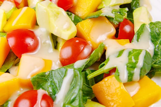 Fresh salad of avocado, mango, spinach and cherry tomatoes, close-up. High quality photo