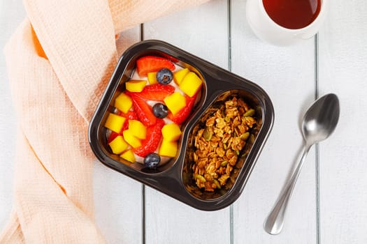Dessert of cream, mango, strawberries and muesli on a wooden background. High quality photo