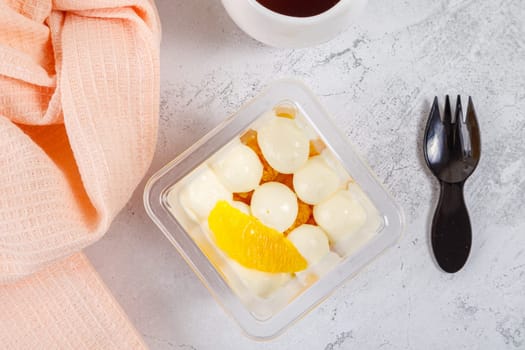 Dessert of cream, jam and orange in a plastic glass on a concrete background. High quality photo